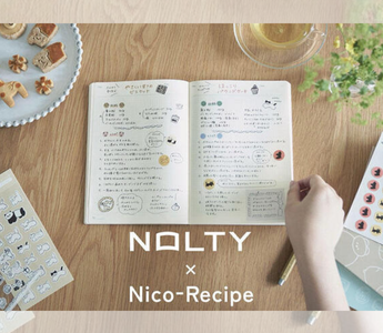 Flat lay of notebooks, washi stickers, and sticky notes from the NOLTY × Nico-Recipe stationery collaboration, featuring warm stamp-style designs for journaling, planning, and everyday writing.